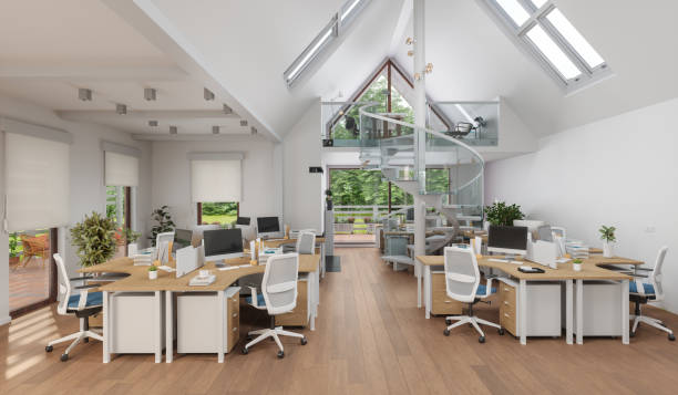 Modern open-plan office with skylights, a glass spiral staircase, wood desks, and white ergonomic chairs